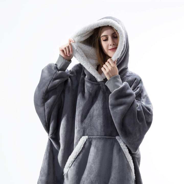 Frau in grauem, flauschigem Oversize-Hoodie mit Kapuze, gemütliche Winterbekleidung.