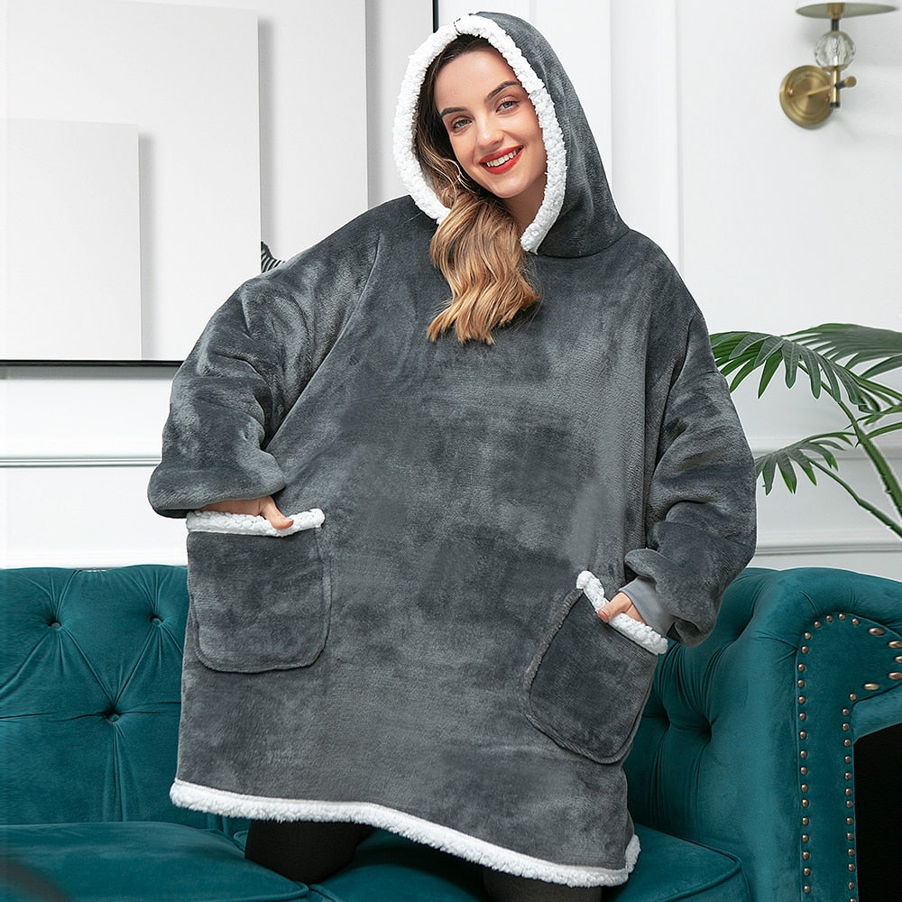 Frau in grauem, flauschigem Oversize-Hoodie mit Kapuze und Taschen, gemütliche Winterkleidung.