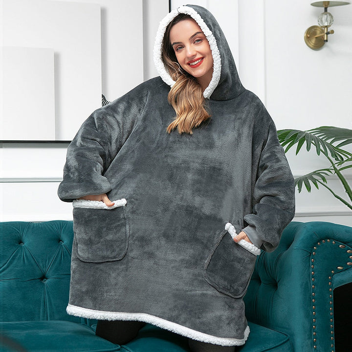 Frau in grauem, flauschigem Oversize-Hoodie mit Kapuze und Taschen, gemütliche Winterkleidung.