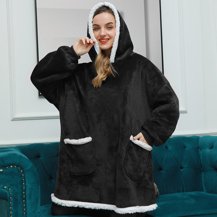 Frau in schwarzem, flauschigem Hoodie-Decke mit Kapuze und Taschen, gemütliche Winterkleidung.